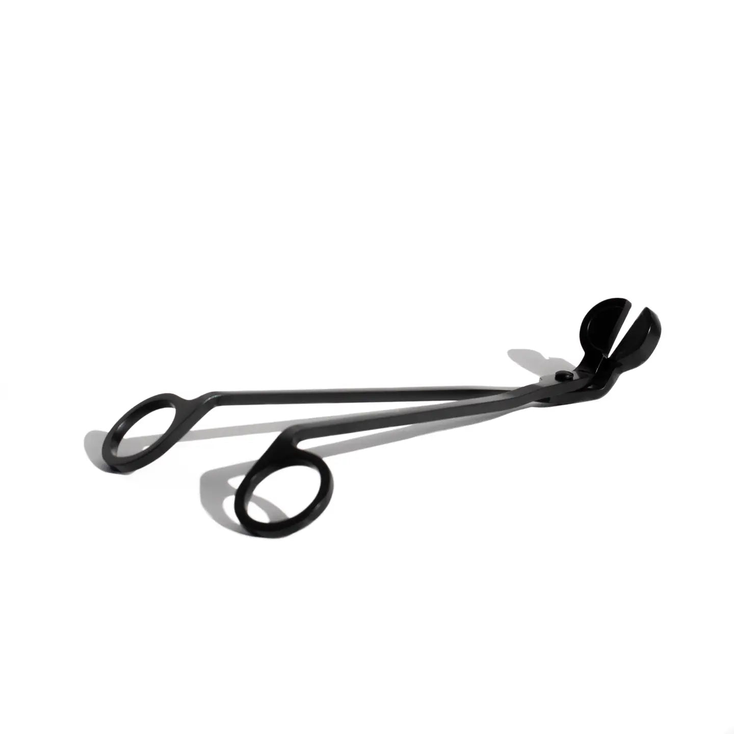 Close-up of sleek black metal wick trimmer with precision blades – functional and stylish tool for candle maintenance and longer burn times.