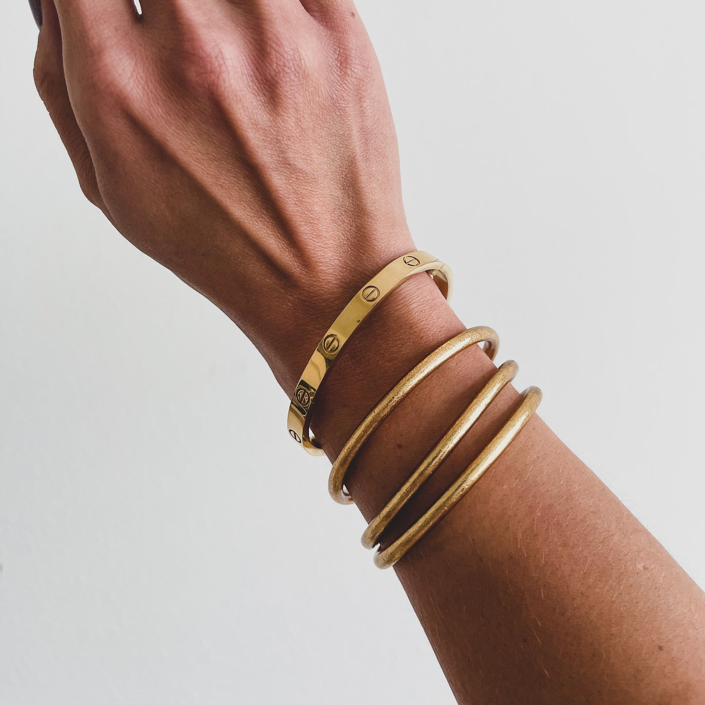 Authentic Buddha Bangles handmade in Thailand, stacked on wrist – blessed by Buddhist monks and lined with gold leaf for spiritual protection and good luck.