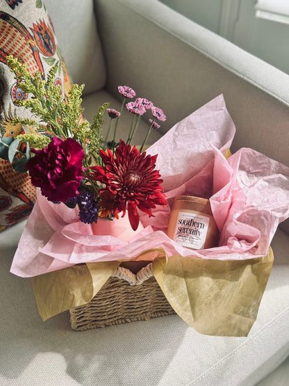 Fresh floral arrangement and non-toxic coconut apricot wax candle inside The Wildflower Gallery Bloom Basket – artisanal gift for local delivery in Texas.