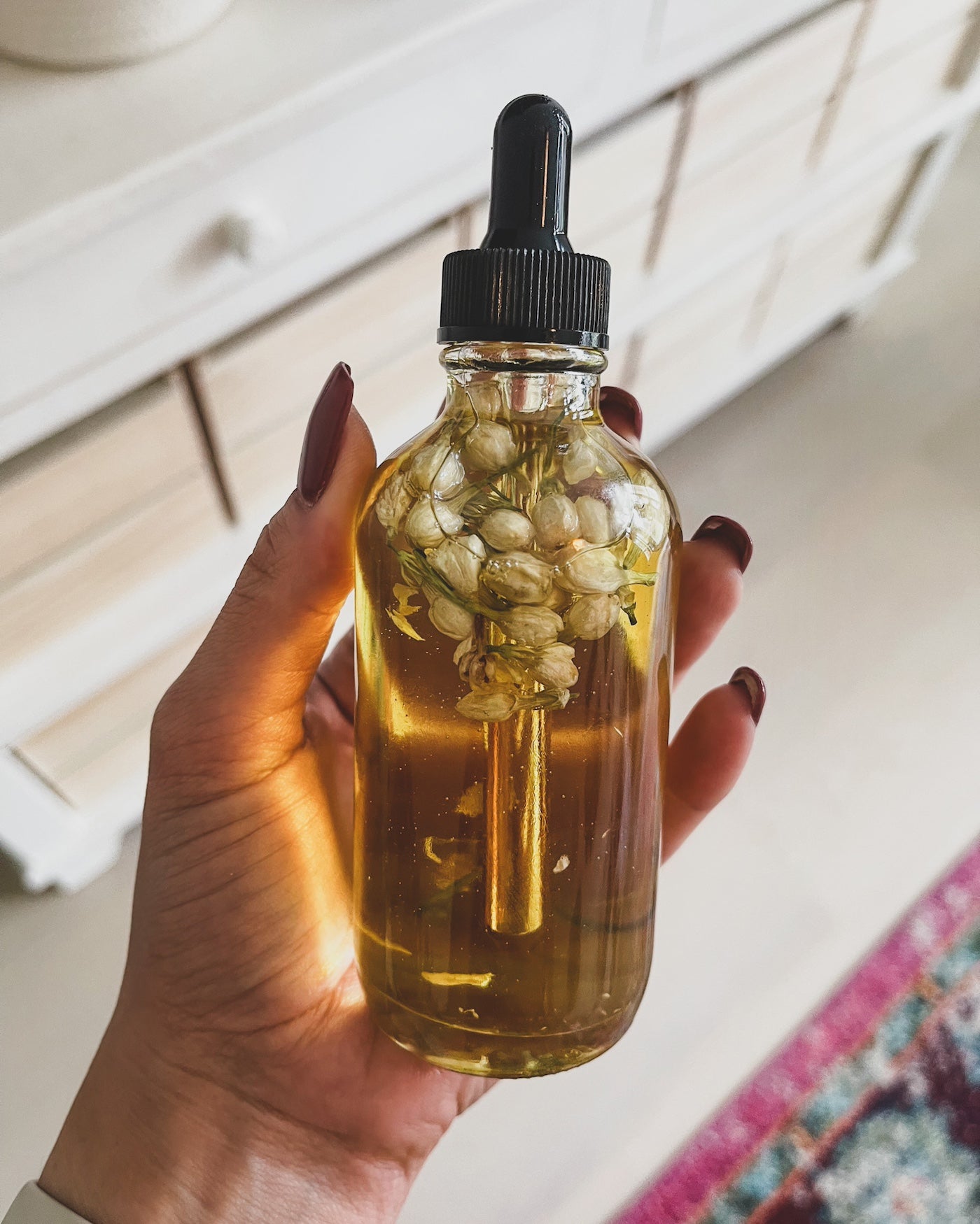hand holding glass jar with flowers and all natural glowing hydration body oil